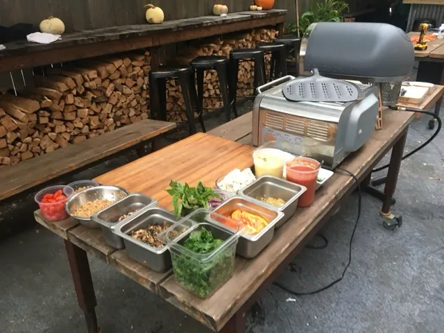 Invitados compartiendo pizzas recién horneadas en evento Figata